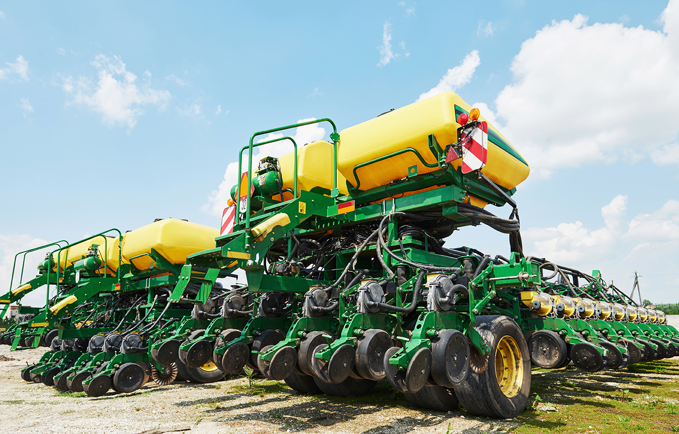 Close up of seeder attached to tractor in field. Agricultural machinery for spring works sowing, seeding